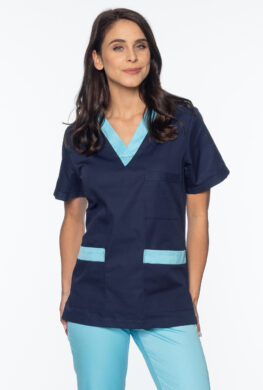 Pielęgniarka ubrana w granatową bluzę medyczną i jasno-niebieskie spodnie medyczne.
